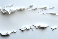 Torn white paper with rough edges creating abstract minimalist composition on light background. Natural shadows emphasize textural depth and layered effect.