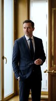 Professional middle-aged Caucasian businessman in navy suit standing confidently in luxury office doorway with natural lighting and elegant interior.