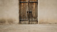 Rustic wooden doors with metal hinges and latch against weathered wall, vintage architecture detail for home decor and design projects.