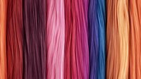 Colorful straight hair extensions in vibrant rainbow shades arranged vertically showing different tones from red to pink, purple, blue and blonde. Macro beauty shot.