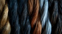 Diverse hair extensions in natural colors from blonde to black, showcasing different textures and tones for beauty and fashion industry use.