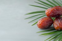 Fresh medjool dates on green palm leaf against light background, healthy natural dried fruit closeup with copy space for food design.