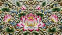 Ornate lotus flower embroidery with golden scrollwork and decorative flourishes on fabric textile background for luxury design projects.