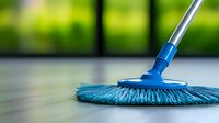 Professional blue microfiber mop on wooden floor against blurred green background, cleaning equipment in action with selective focus on mop head.