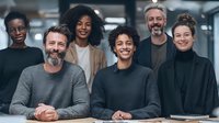 Diverse professional team smiling in modern office environment, representing workplace collaboration and corporate culture.