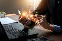 Business professional analyzing financial data on smartphone with glowing growth chart overlay at modern office desk with laptop for investment planning.
