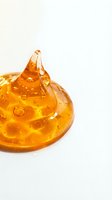Golden amber gel or liquid forming a dome shape with a peak on white background, isolated for design use in cosmetics, skincare, wellness and beauty product packaging.