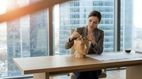 Professional businesswoman enjoying healthy lunch at modern office desk with city skyline view through large windows during bright sunny day.