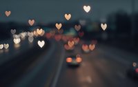 Romantic heart-shaped bokeh lights over blurred city street at night creating dreamy Valentine's Day atmosphere for love-themed designs and greeting cards.