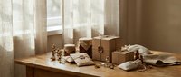 Wrapped gift boxes with kraft paper and twine on wooden table by window with natural light for holiday celebrations and special occasions.