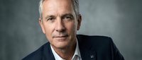 Middle-aged Caucasian male professional in dark blazer and white shirt against neutral gray background, suitable for corporate, business, and leadership concepts.
