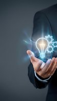 Businessman holding glowing lightbulb with gears representing innovation, creativity and business solutions for corporate presentations and marketing.