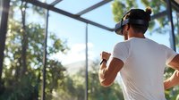 Young Asian man in white t-shirt exercising on modern treadmill with VR headset at home gym, sunlight streaming through windows, fitness and technology concept.