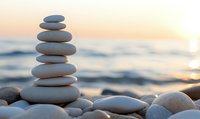 Balanced stone cairn on beach at sunset with calm ocean waves, symbolizing meditation, wellness, and harmony in nature.