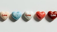 Colorful heart-shaped candies with love text arranged in row on white background. Sweet romantic message concept for valentines day and anniversary celebrations.