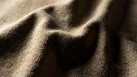 Neutral beige linen fabric with natural texture and soft shadows, suitable for fashion, interior design, and textile backgrounds.