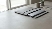 Modern minimalist workspace with closed laptop and tablet stacked on clean desk surface near window with natural light for productivity and technology concepts.
