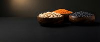 Wooden bowls filled with white chickpeas, red lentils, and black lentils arranged on dark surface for cooking and nutrition content.