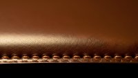 Brown leather surface with decorative stitching edge detail for luxury craftsmanship and premium material design projects.