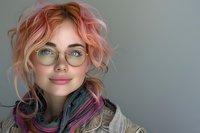 Young woman with pink hair and round glasses smiling at camera, wearing casual scarf and jacket. Natural beauty portrait with soft lighting perfect for lifestyle and fashion blogs.