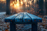 Wooden park bench in autumn forest at sunset, fallen orange leaves on ground, dreamy bokeh light through trees creates magical atmosphere. Peaceful nature scene.