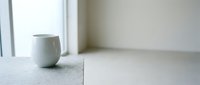 Minimalist ceramic cup on white concrete surface near window with natural light, suitable for home decor and lifestyle design projects.