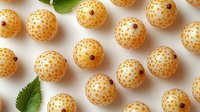 Yellow raspberries arranged in rows on white background with fresh green leaves. Organic summer berries pattern for healthy food design and packaging.
