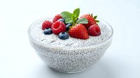Chia seed pudding topped with fresh strawberries, raspberries and blueberries in glass bowl. Healthy breakfast dessert with mint garnish on white background.