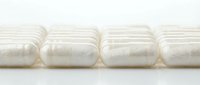 Row of white compressed towel rolls wrapped in plastic packaging on neutral background for hospitality, spa, and hotel linen supply.