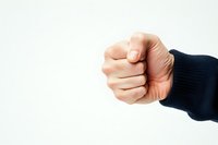 Clenched fist in dark sleeve against white background, symbolizing strength, determination, protest, or aggression in conceptual photography.