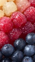 Fresh mixed berries with water drops and frost crystals arranged in rows - raspberries, white raspberries, and blueberries creating gradient pattern. Macro food photography.