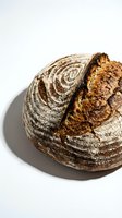 Artisan sourdough loaf with scored crust and golden-brown coloring on white background, ready for bakery, food, and culinary design projects.