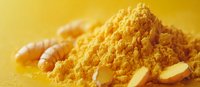 Ground turmeric powder with fresh root pieces scattered on yellow surface, vibrant golden spice macro photography showing texture and natural ingredients.