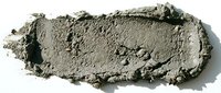 Crushed gray eyeshadow or powder cosmetic swatch with texture and crumbled particles on white background for makeup design.