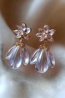 Elegant crystal flower drop earrings with gold details on soft blurred background. Delicate floral studs feature translucent petals and dangle elements.