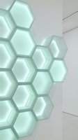 Glowing hexagonal light panels arranged in honeycomb pattern on white wall, emitting soft mint green luminescence in modern interior design.