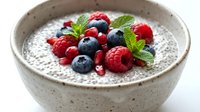 Chia seed pudding topped with fresh blueberries, raspberries and mint leaves in ceramic bowl. Healthy breakfast superfood dessert for wellness nutrition.