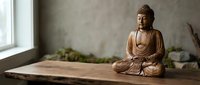 Wooden Buddha statue in meditation pose on rustic table near window with soft natural light creating peaceful zen atmosphere for mindfulness practice.
