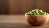 Fresh green fava beans in wooden bowl on rustic brown table background with copy space for text, healthy organic legumes for cooking.