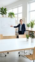 Confident Caucasian businesswoman in navy suit presenting success growth chart on whiteboard in bright modern office with green plants.