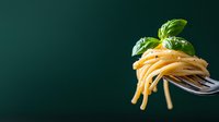 Twirled spaghetti pasta on silver fork with fresh basil leaf garnish against dark green background, minimalist food photography composition.
