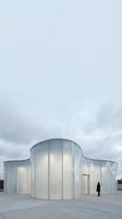 Modern curved glass pavilion with translucent walls on concrete plaza, featuring contemporary architecture design for commercial, institutional, or exhibition spaces.