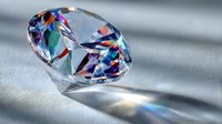 Brilliant cut diamond with colorful light refraction creating rainbow prism effect on soft gray surface, showcasing luxury gemstone sparkle.