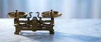 Vintage brass balance scale with two pans on marble surface, antique weighing instrument for justice, law, pharmacy or kitchen use in retro style.