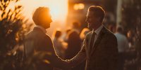 Two professional businessmen shaking hands during golden hour sunset, corporate partnership agreement meeting outdoors in urban setting.