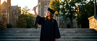 Young Hispanic woman graduate celebrating with diploma on university campus steps during golden hour sunset, academic achievement and success milestone.