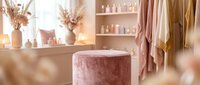 Luxurious spa and wellness salon interior with pink velvet ottoman, dried flowers, skincare products on shelves, and soft lighting for beauty and relaxation business concepts.