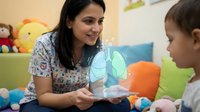 Female pediatric nurse with stethoscope engaging with young patient in colorful hospital playroom during medical consultation and care.