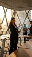 Professional businesswoman presenting data analytics on transparent screen in modern office conference room during golden hour meeting.