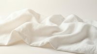 Soft white cotton fabric with natural wrinkles and folds creating gentle shadows and texture on neutral background for textile and fashion design projects.